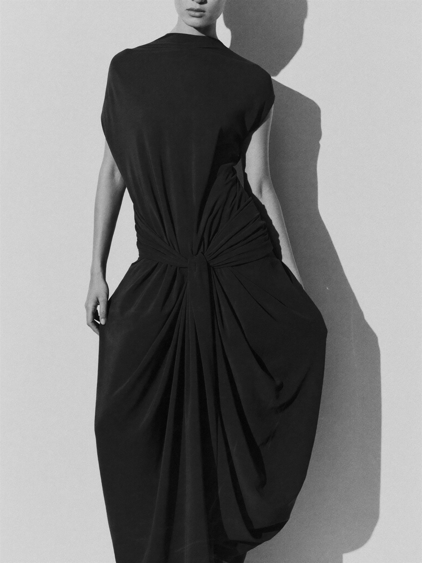 Full-length monochrome study of a draped black garment with soft gathered fabric.